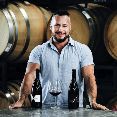 Exprimere proprietor John Dimos with wine bottles